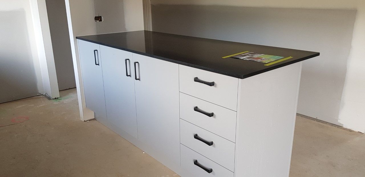 A Kitchen With A Black Counter Top And White Cabinets — Southeast Stone Pty Ltd In Caloundra, QLD