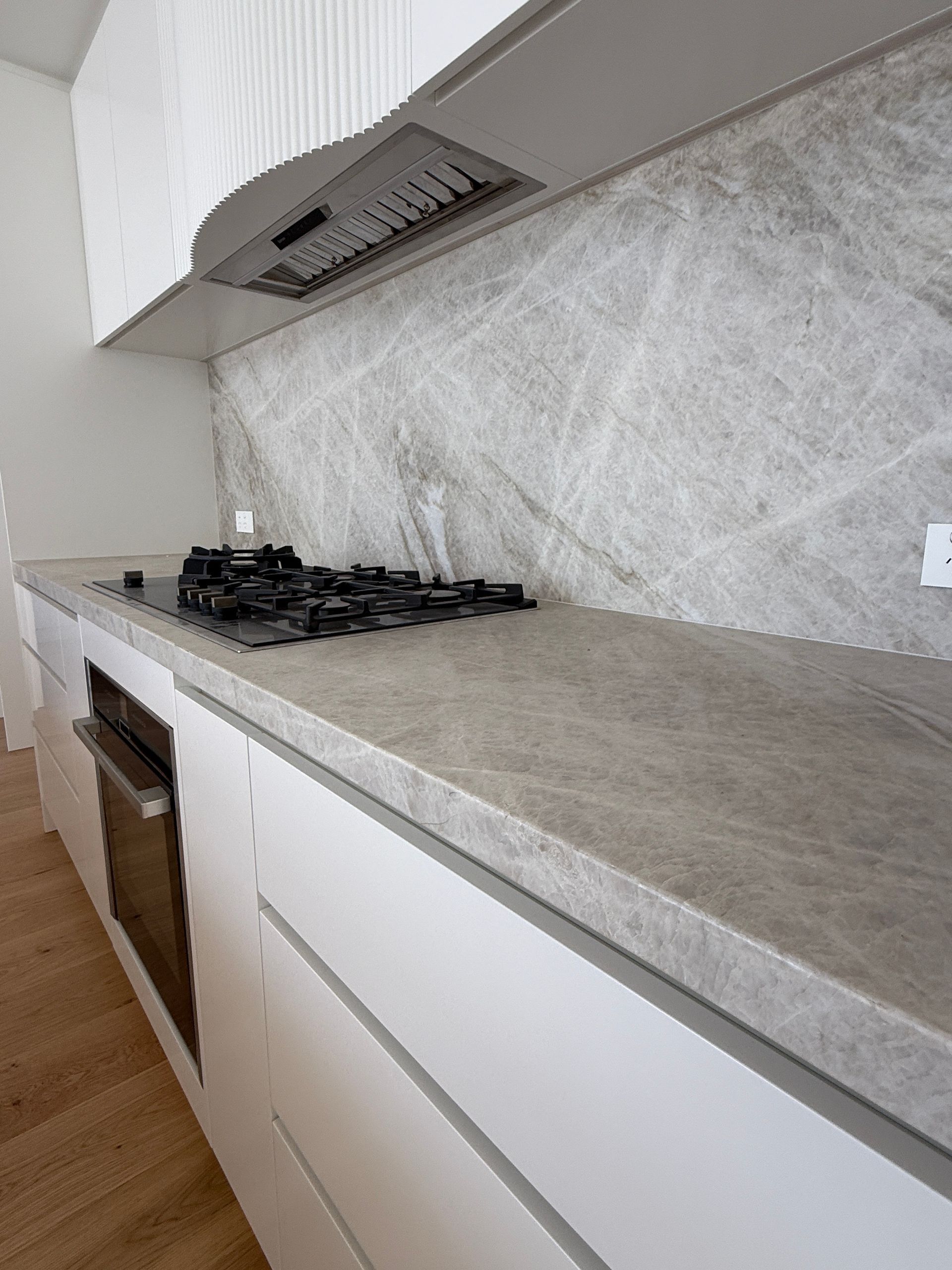 Modern kitchen with grey marble backsplash and countertops, white cabinets— Southeast Stone Pty Ltd In Caloundra West, QLD