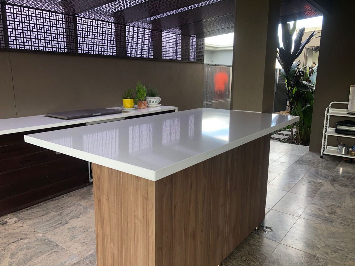 A Kitchen With A Large Wooden Island And A White Counter Top — Southeast Stone Pty Ltd In Sunshine Coast, QLD