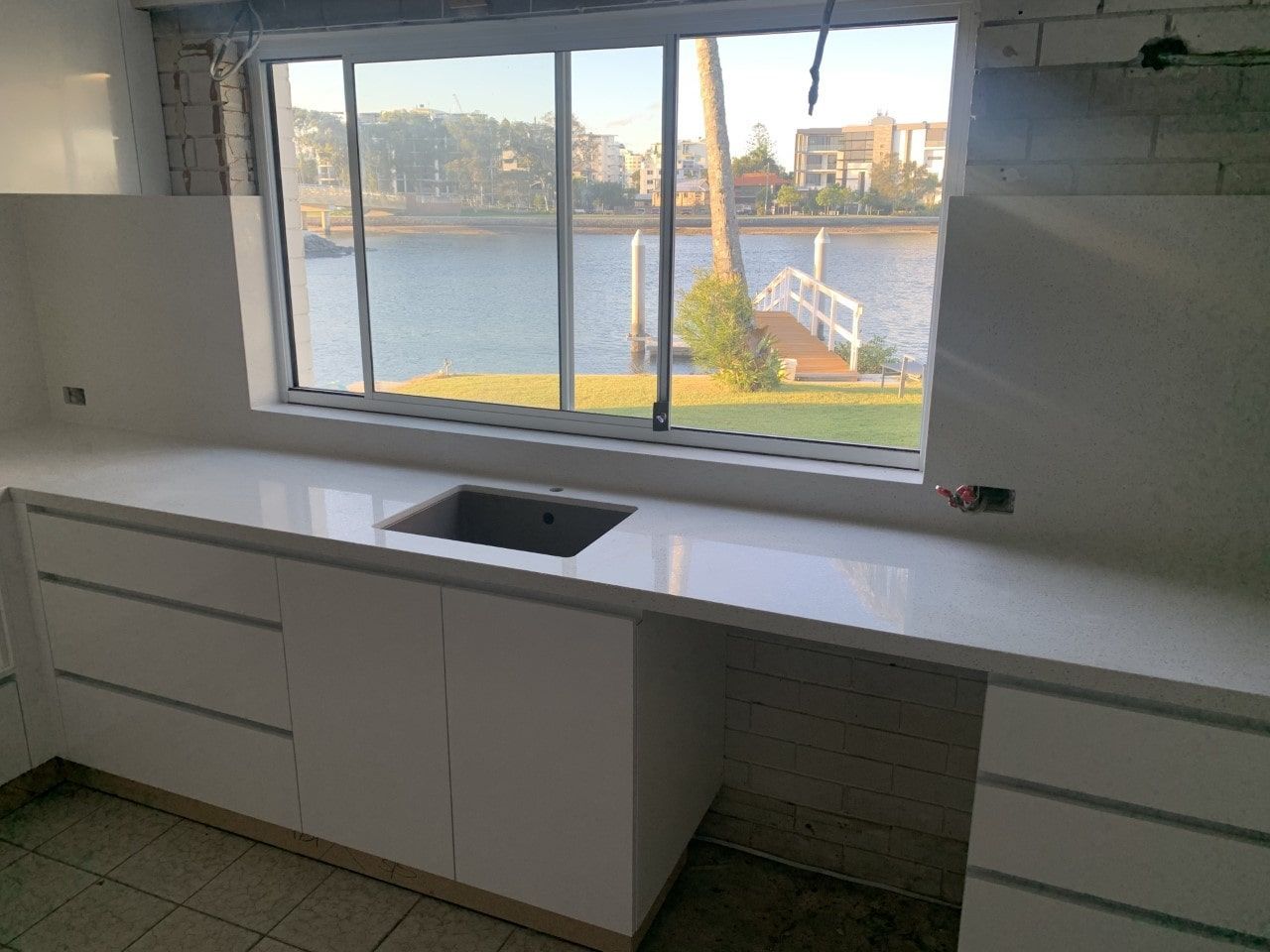 A Kitchen With A Sink And A Window Overlooking A Body Of Water — Southeast Stone Pty Ltd In Brisbane, QLD