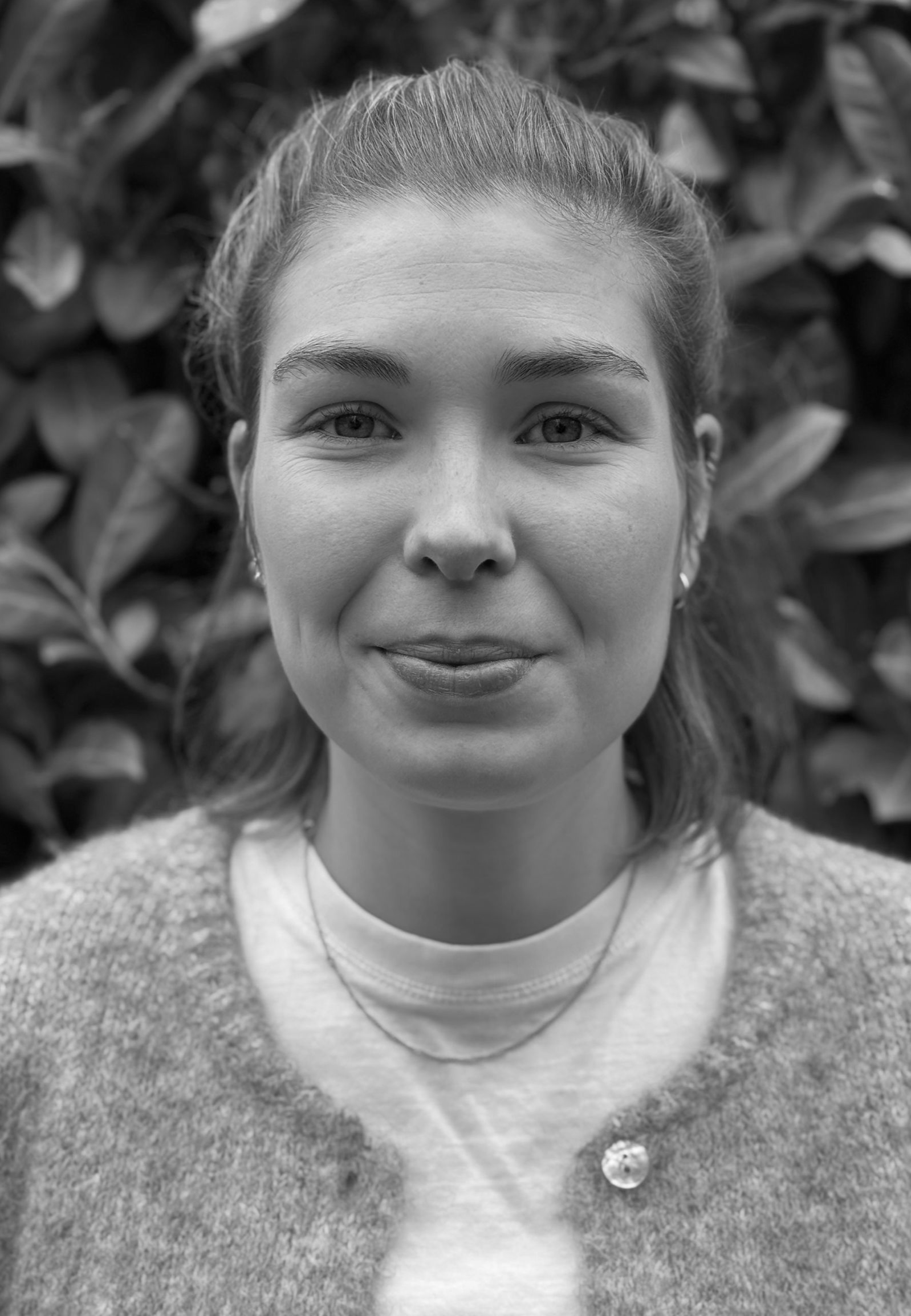 A woman in a black shirt is smiling in a black and white photo.