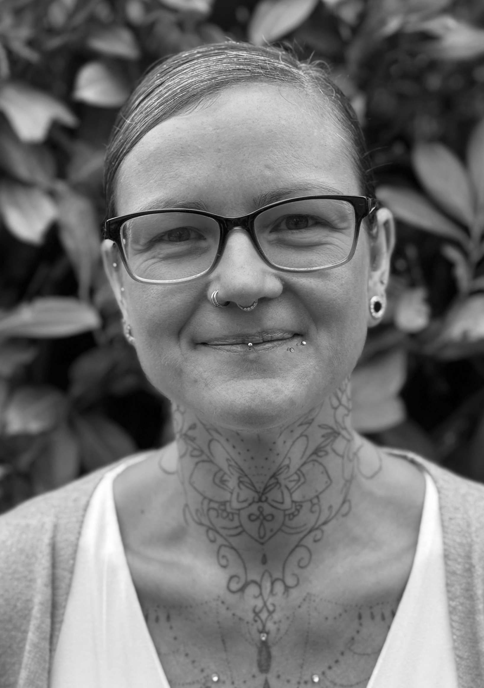 A woman in a black shirt is smiling in a black and white photo.