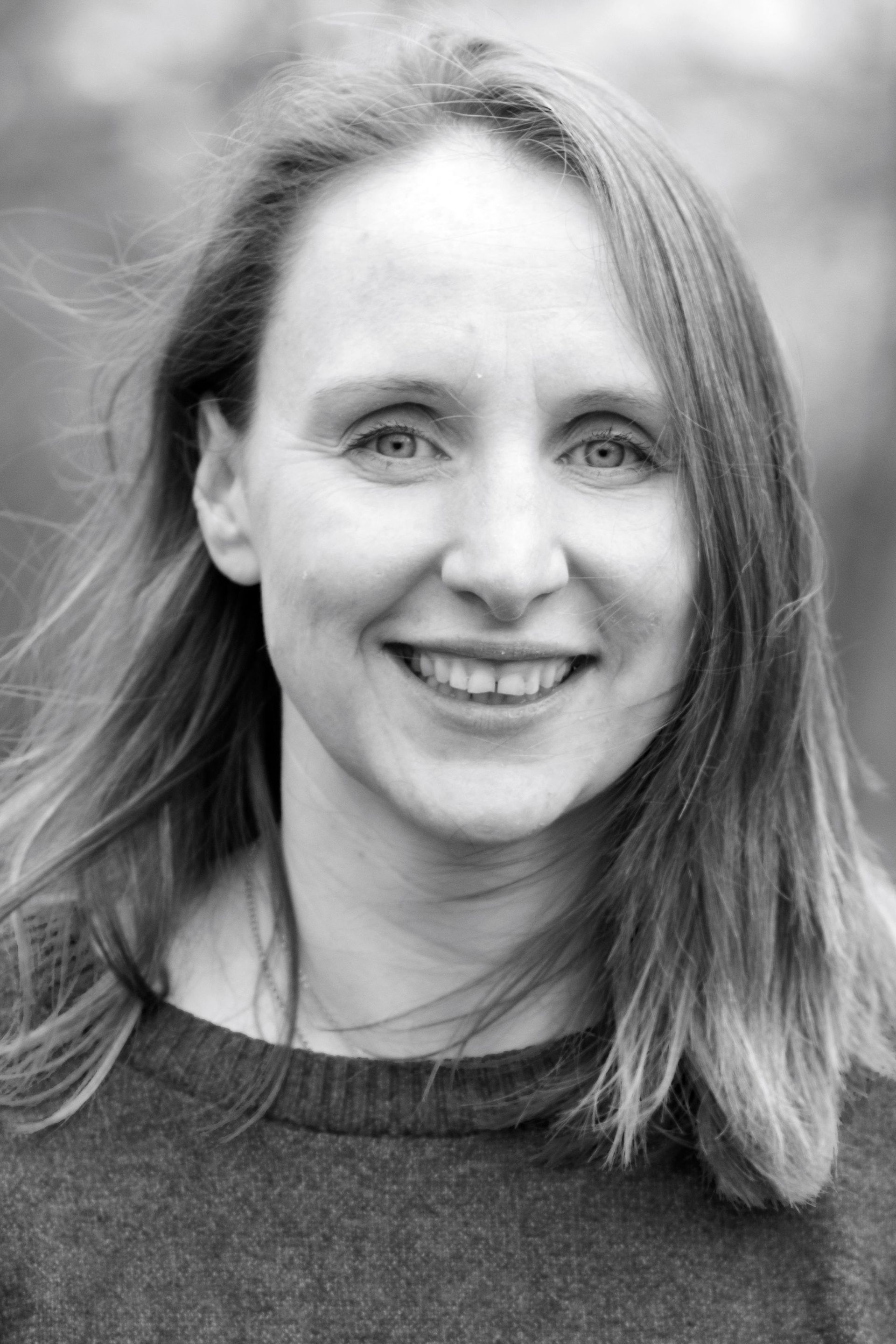 A woman with long hair is smiling in a black and white photo.