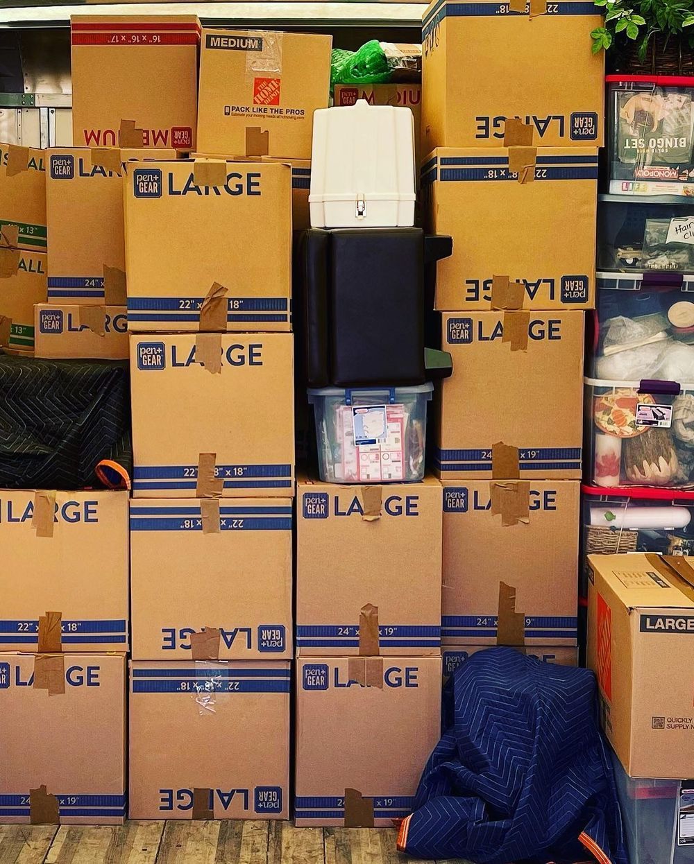 Stacked cardboard boxes and packed bags piled in a storage area or warehouse.
