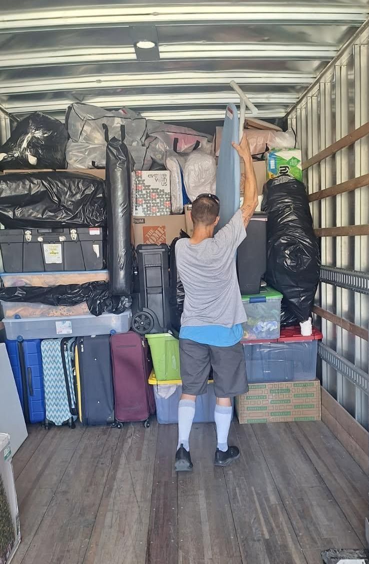 Person unloading packed boxes and hanging bags in a moving truck interior