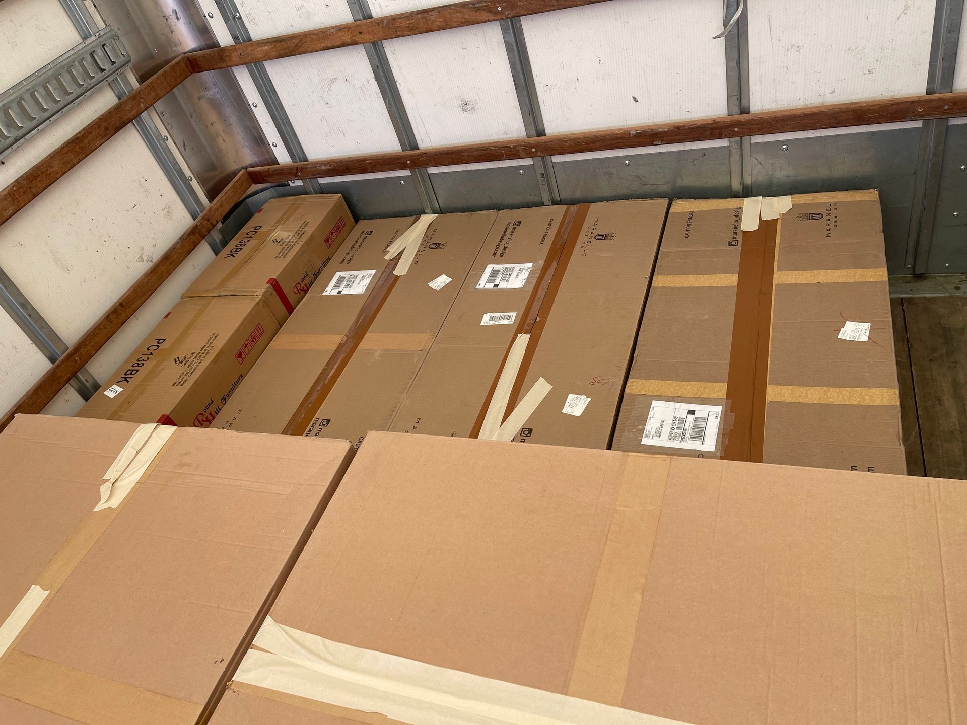 Stacked cardboard boxes in a truck trailer, secured with packing tape.
