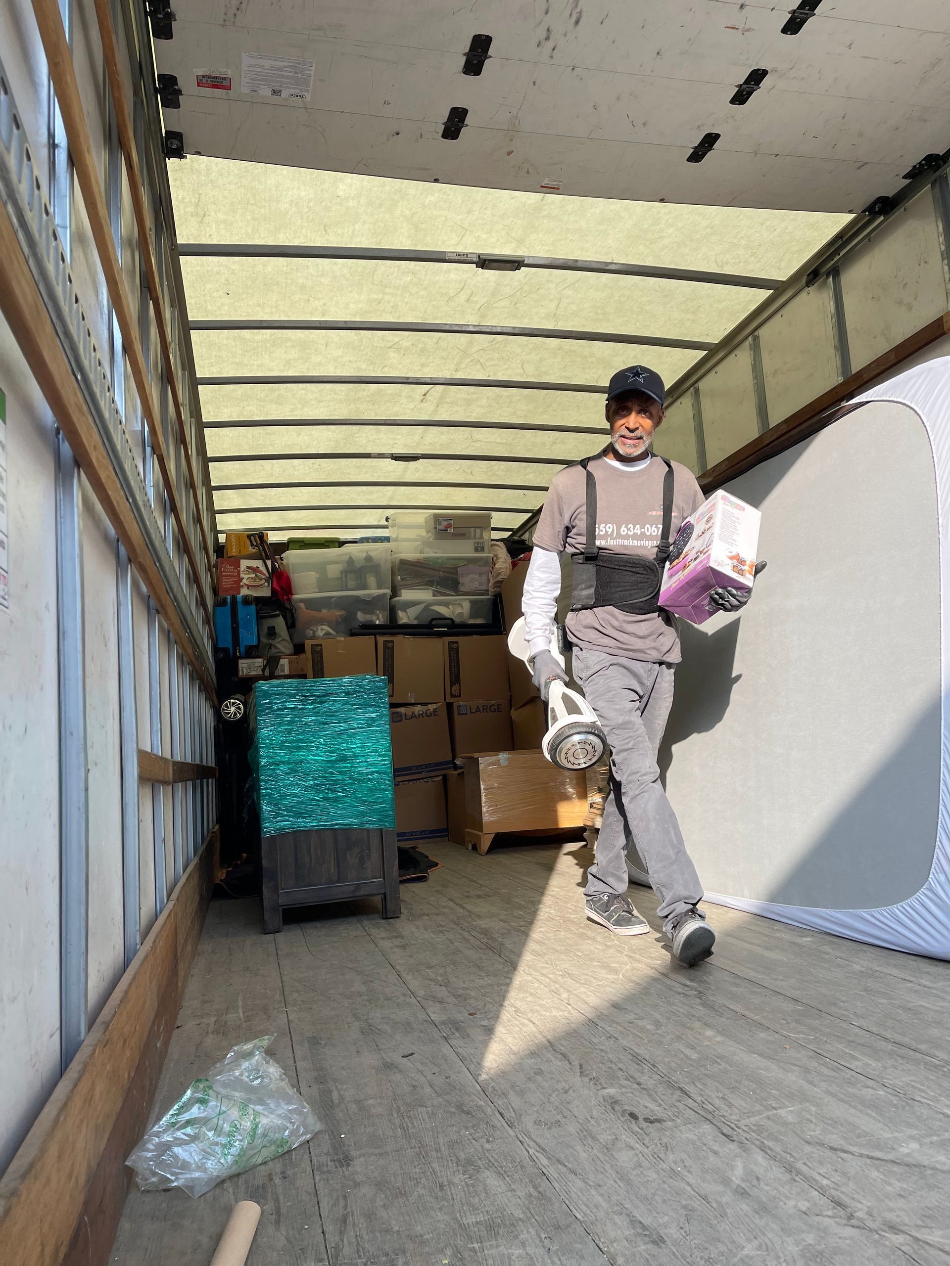 Person walking inside a moving truck beside packed boxes and a large white mattress.