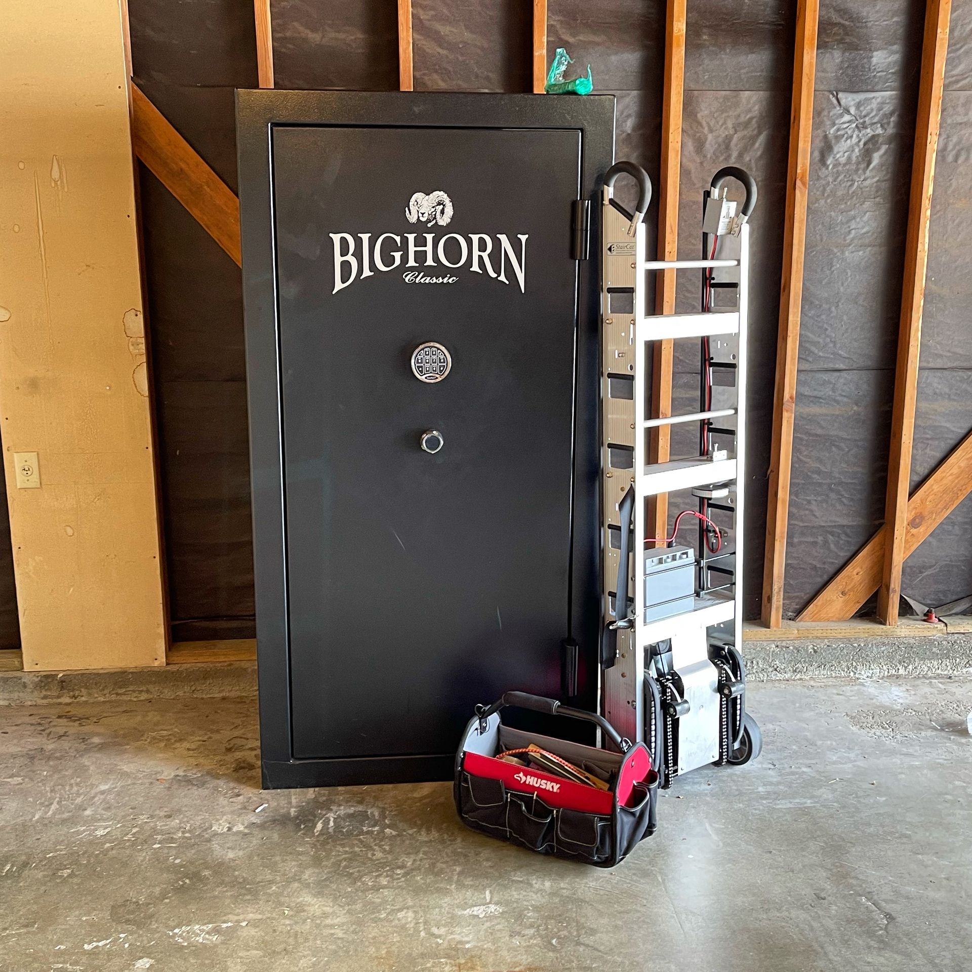 Black Bighorn gun safe with a white ladder and red tool bag in a garage-like room