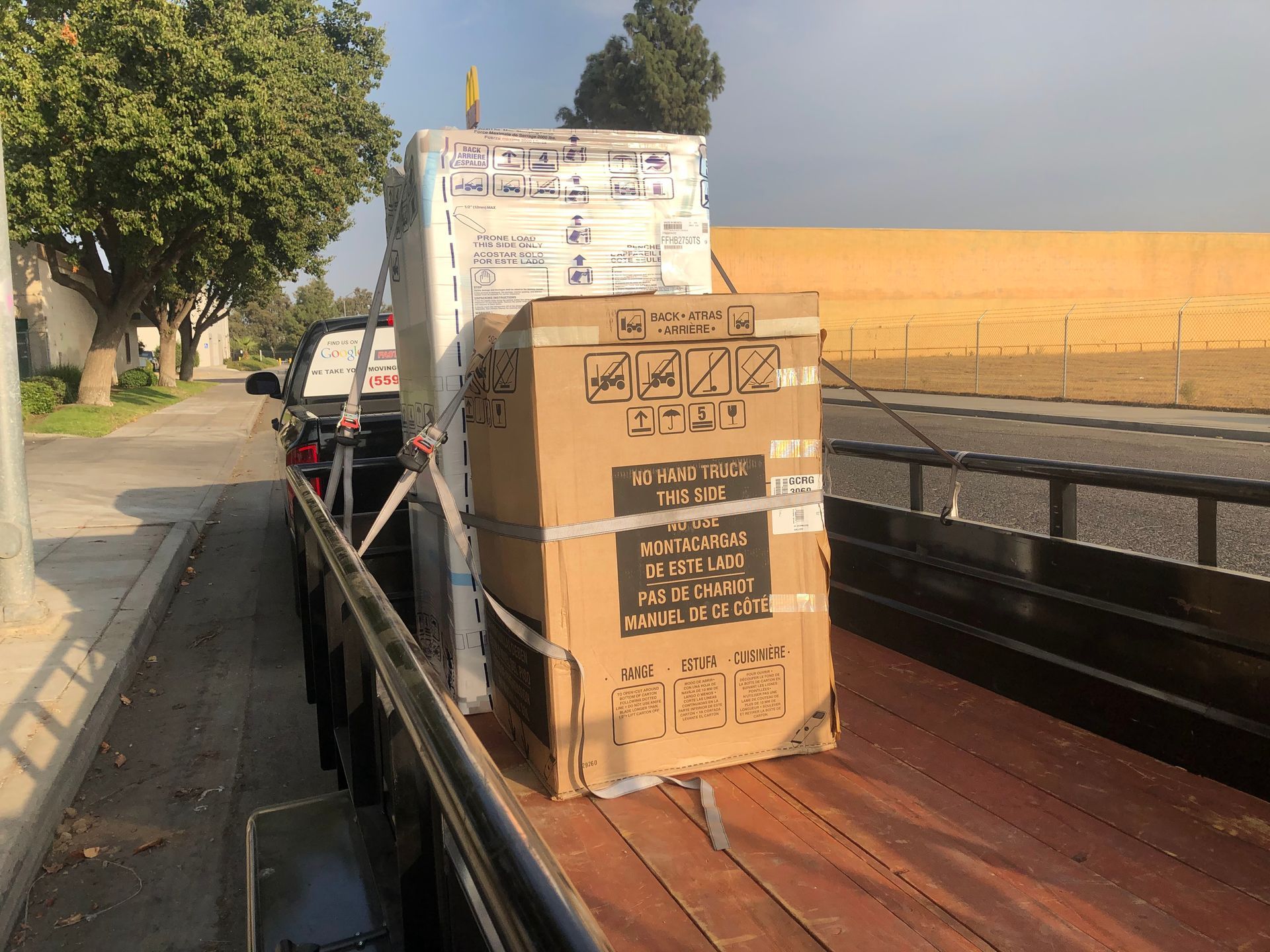 Truck bed loaded with stacked cardboard boxes and crates on a roadside.