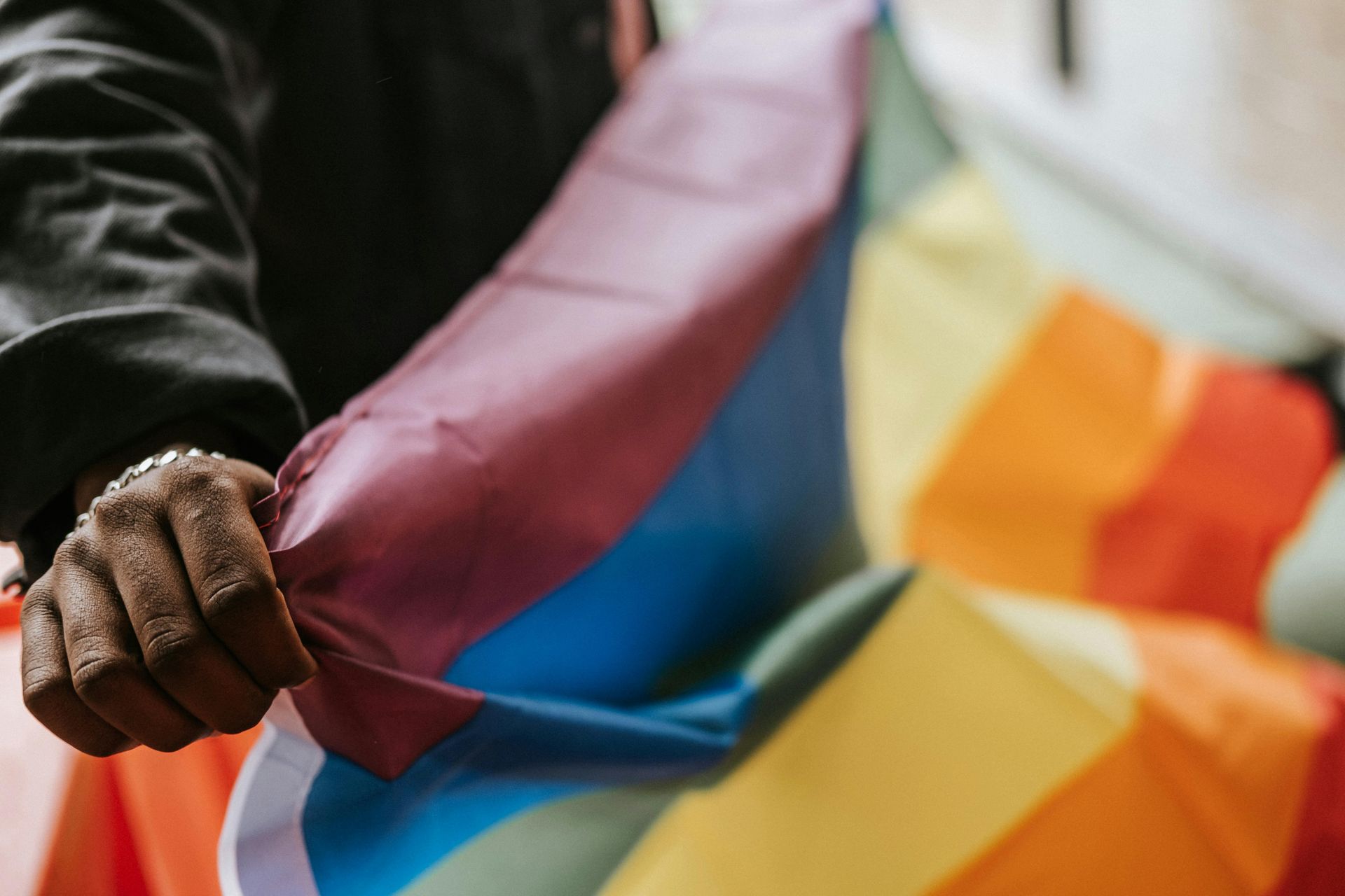 Pessoa segurando uma bandeira do orgulho LGBTQ+ com as cores do arco-íris