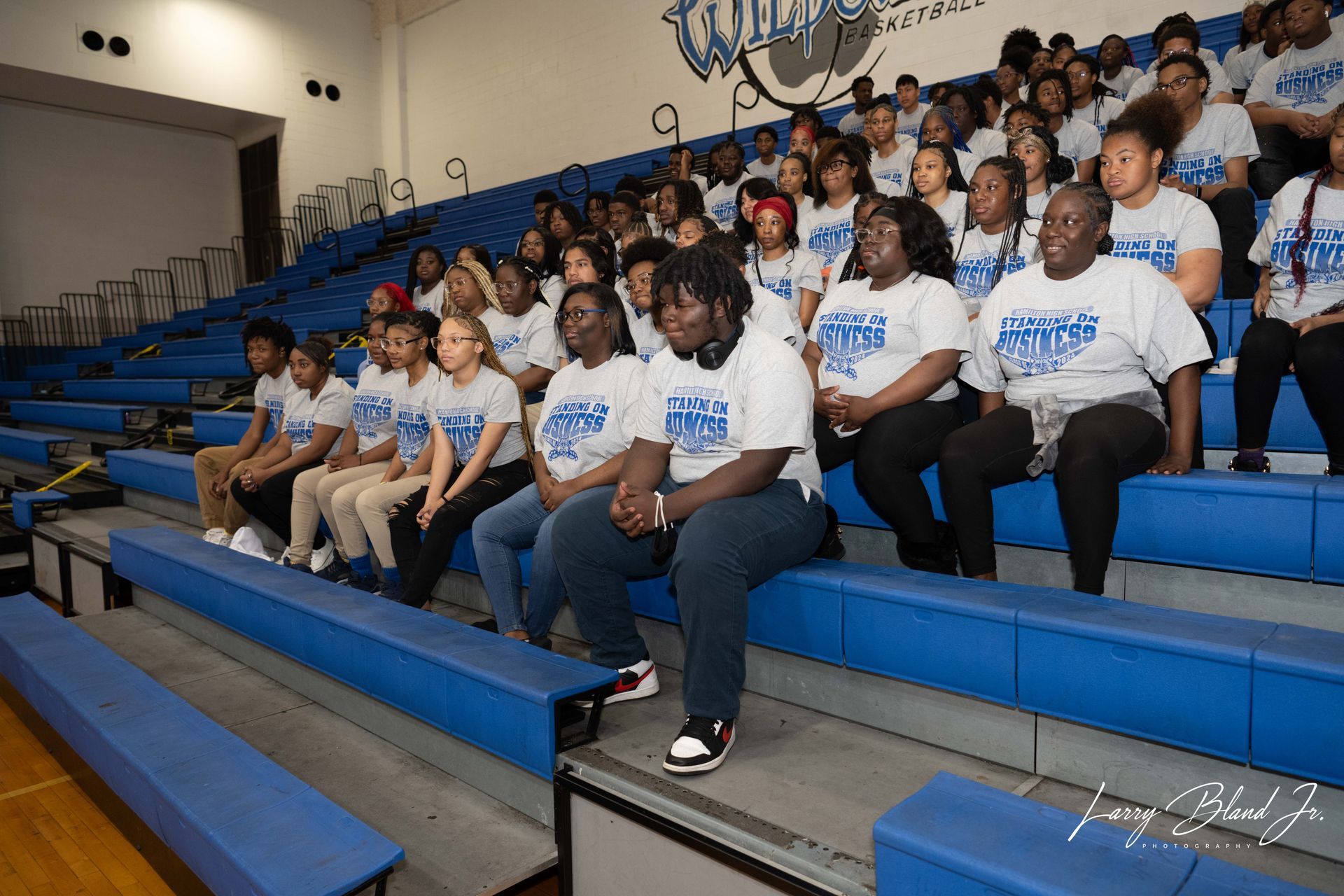 Group of people in matching shirts seated in a school bleacher.