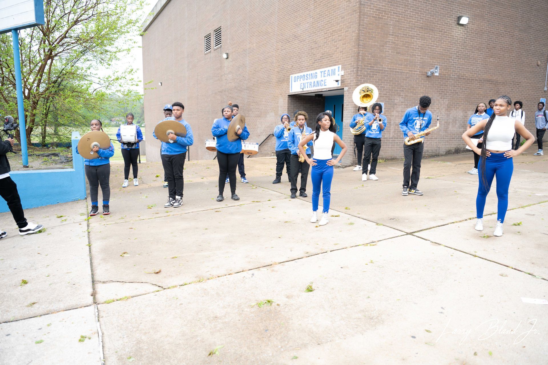 School band performing outdoors, wearing blue and white uniforms.