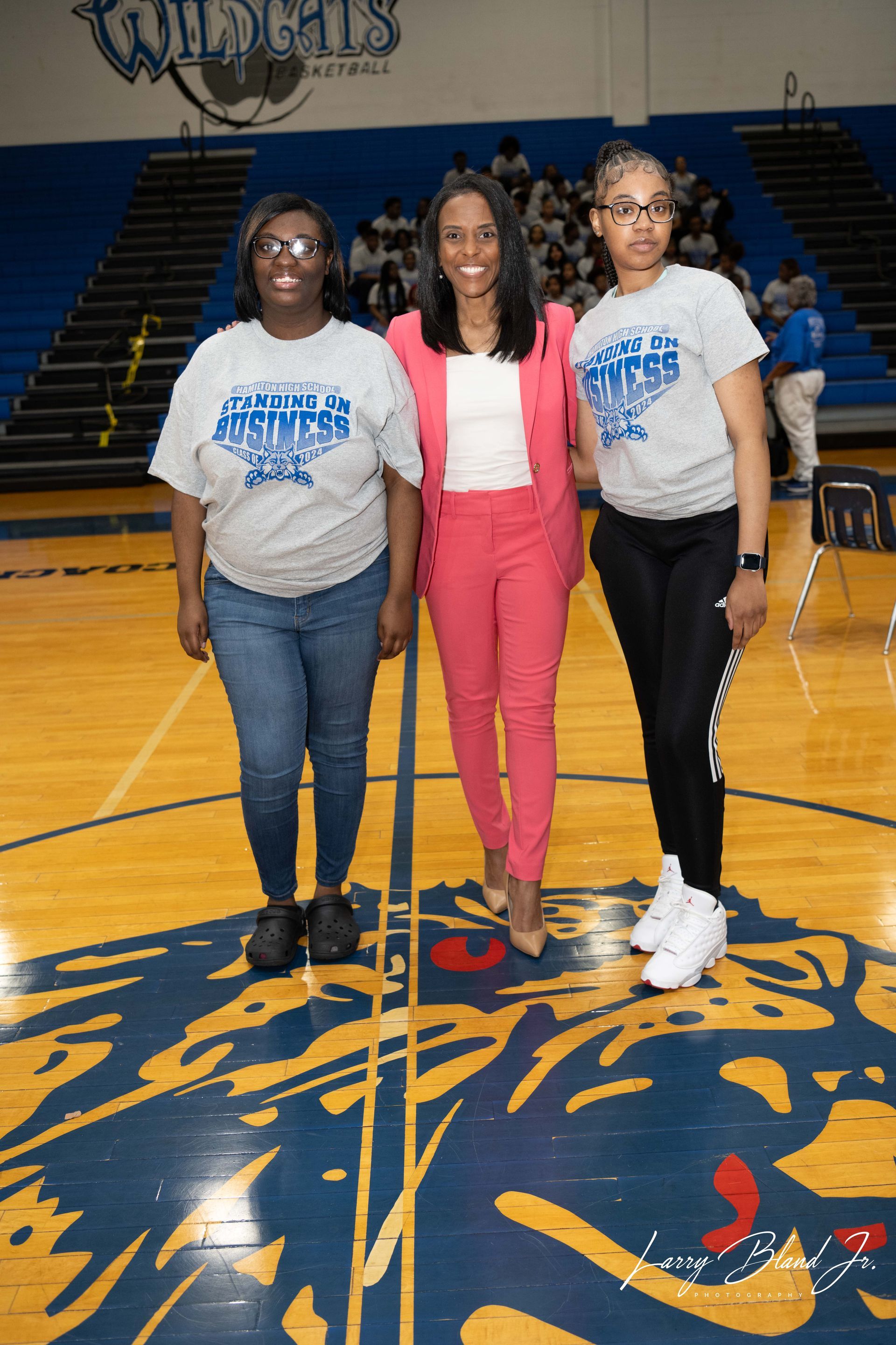 Three people stand on a basketball court. 