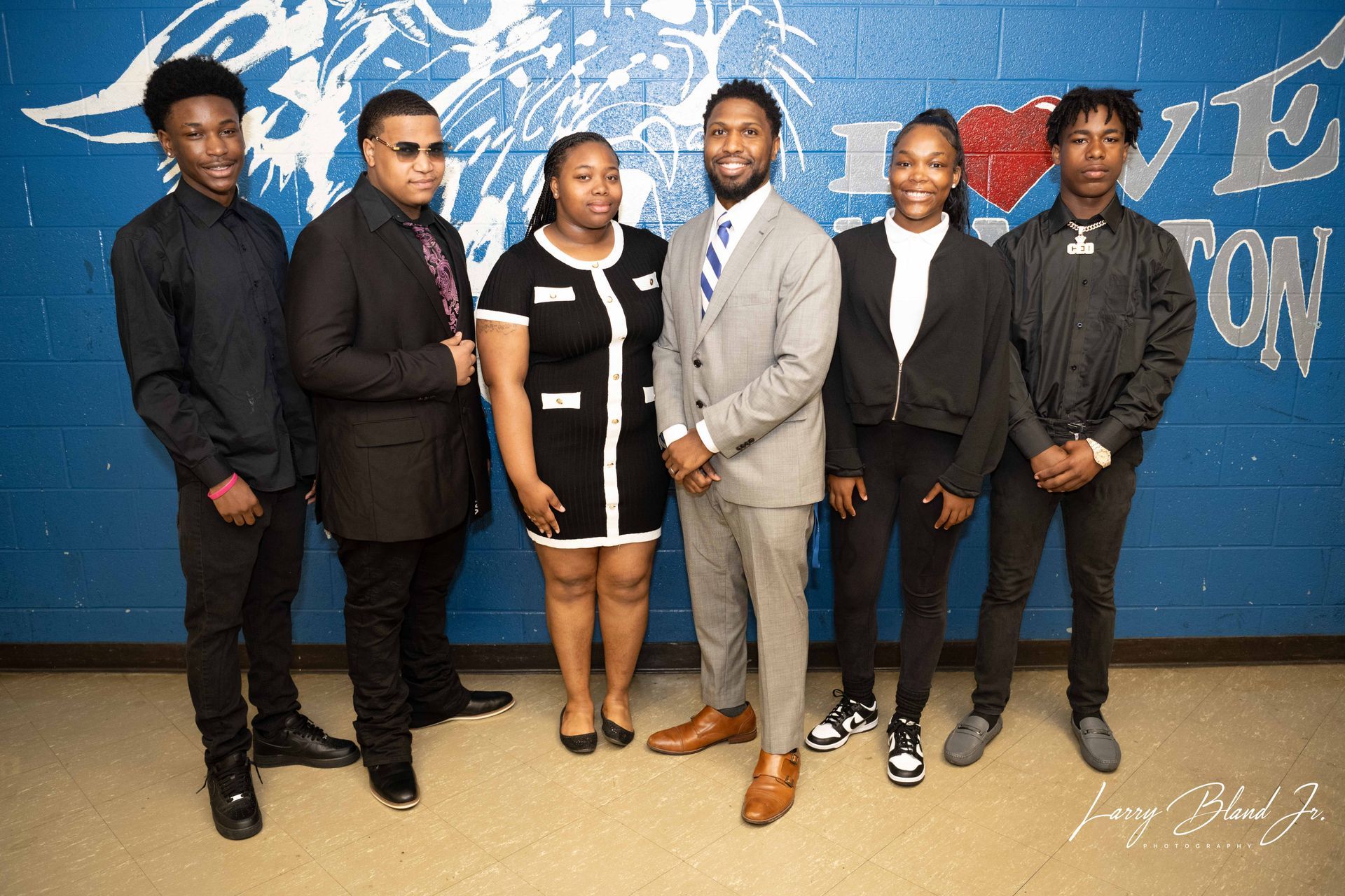 Group of people standing in front of a blue wall with a logo.
