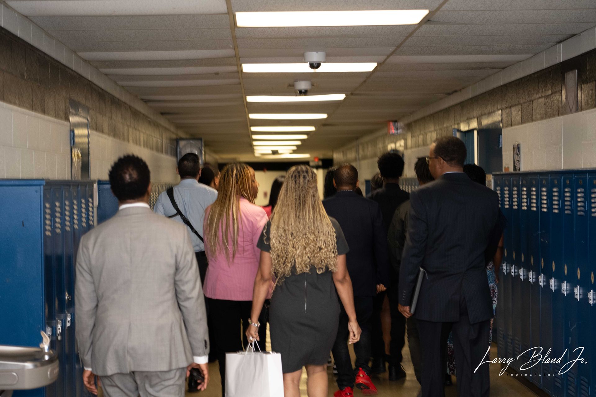 People walking down a school hallway lined with blue lockers.
