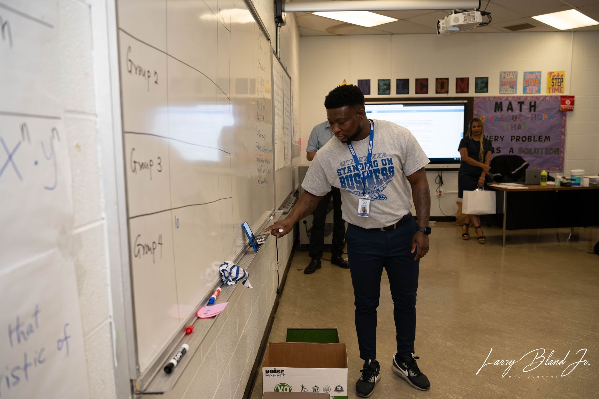 Teacher demonstrates a lesson with model airplanes on a whiteboard in a classroom.