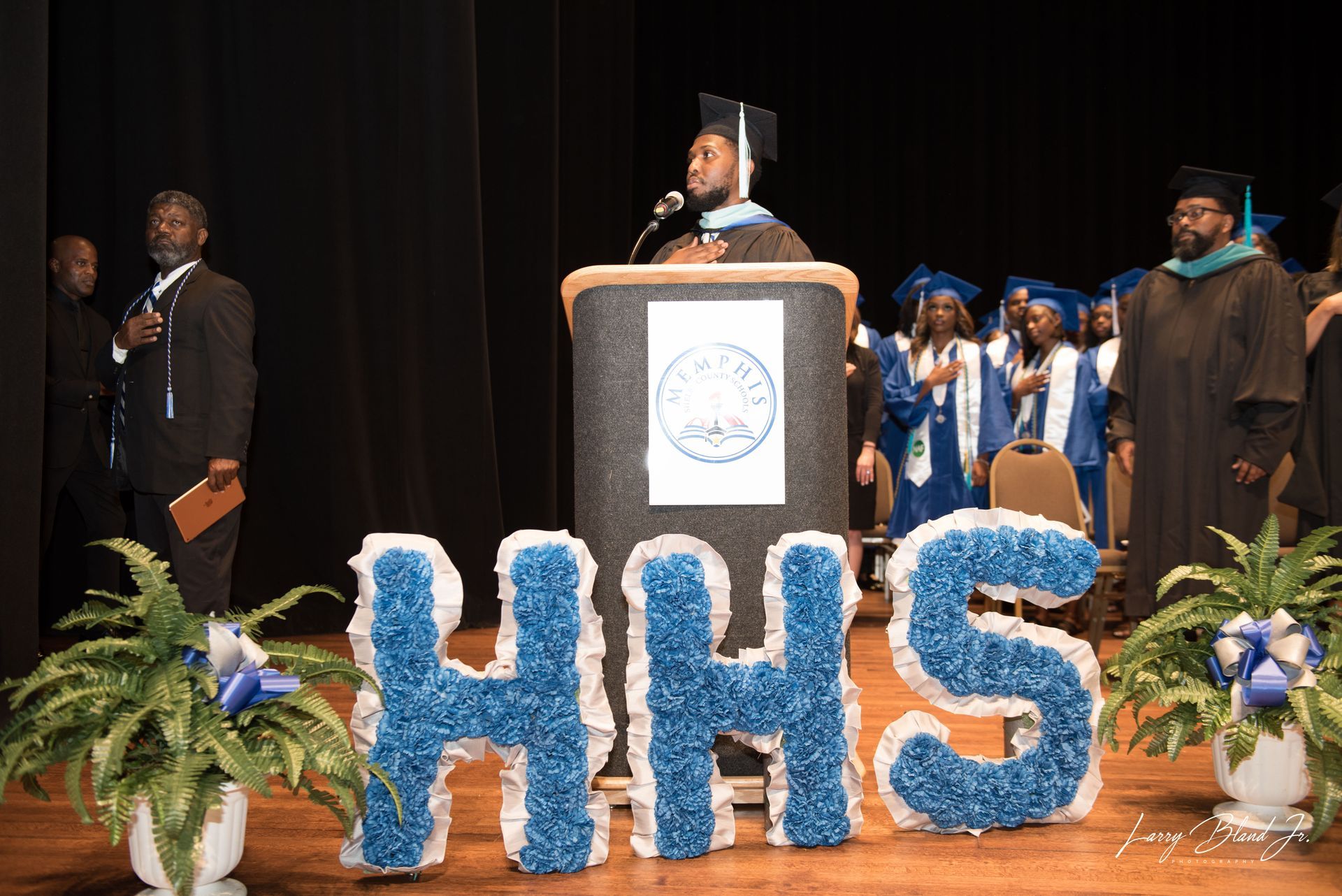 A graduate giving a speech at a podium on a stage with 