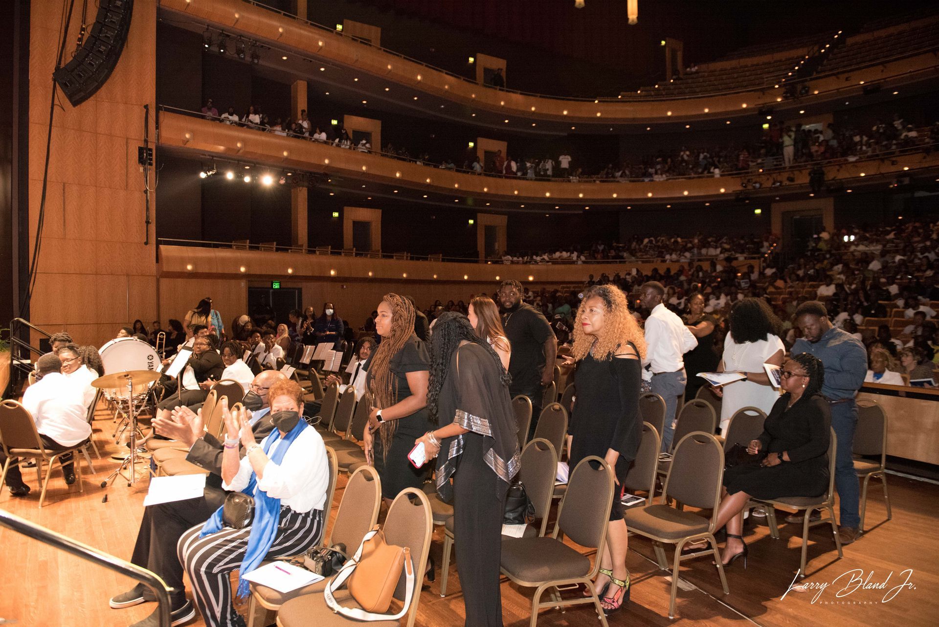 Audience in an auditorium; several people standing and sitting.