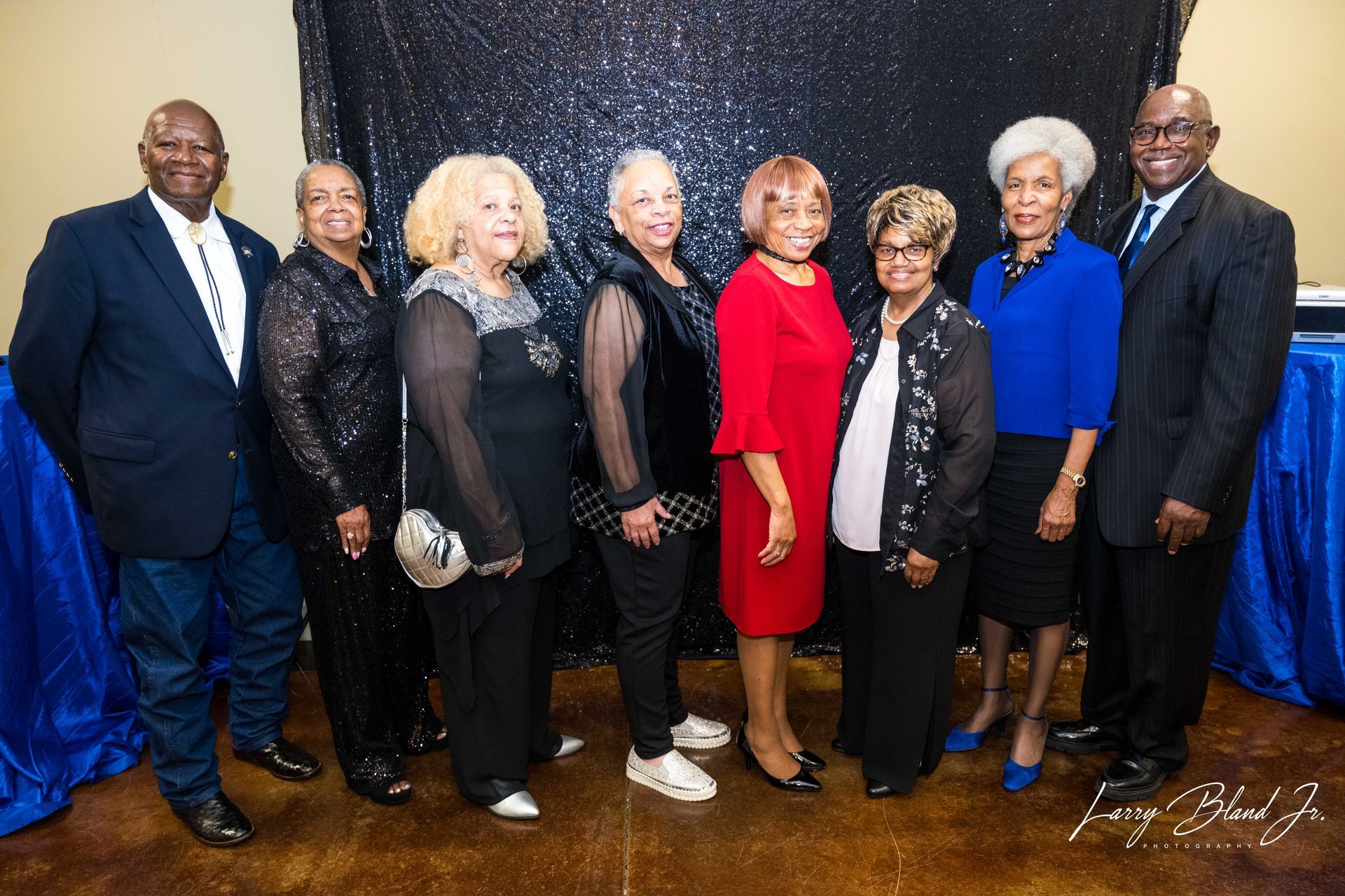 Group of people at an event, standing in front of a blue and black background.