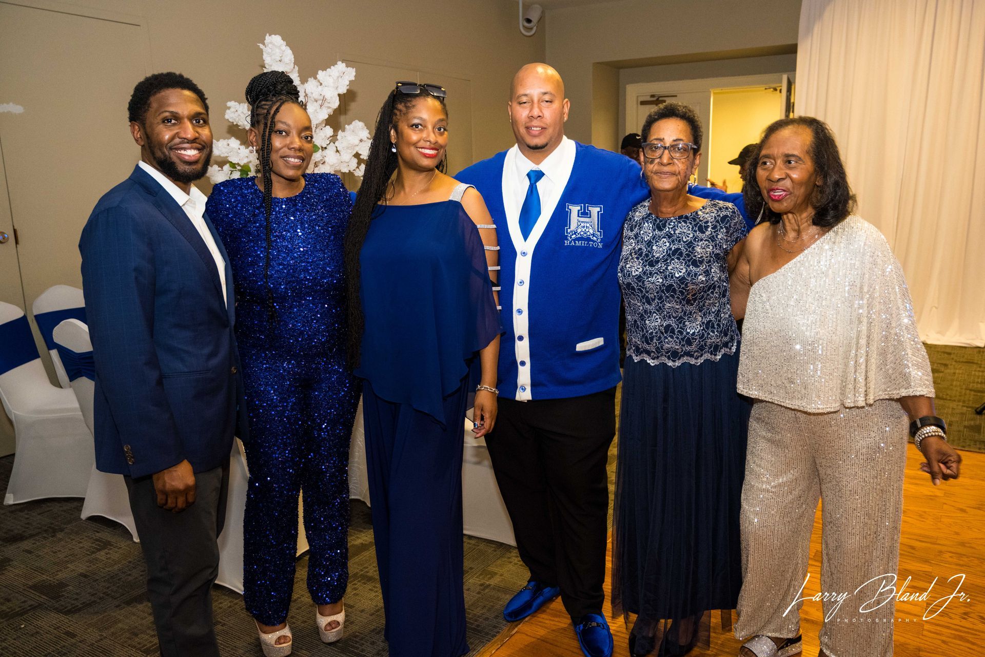 Group of people in blue formal wear, posing at an indoor event.