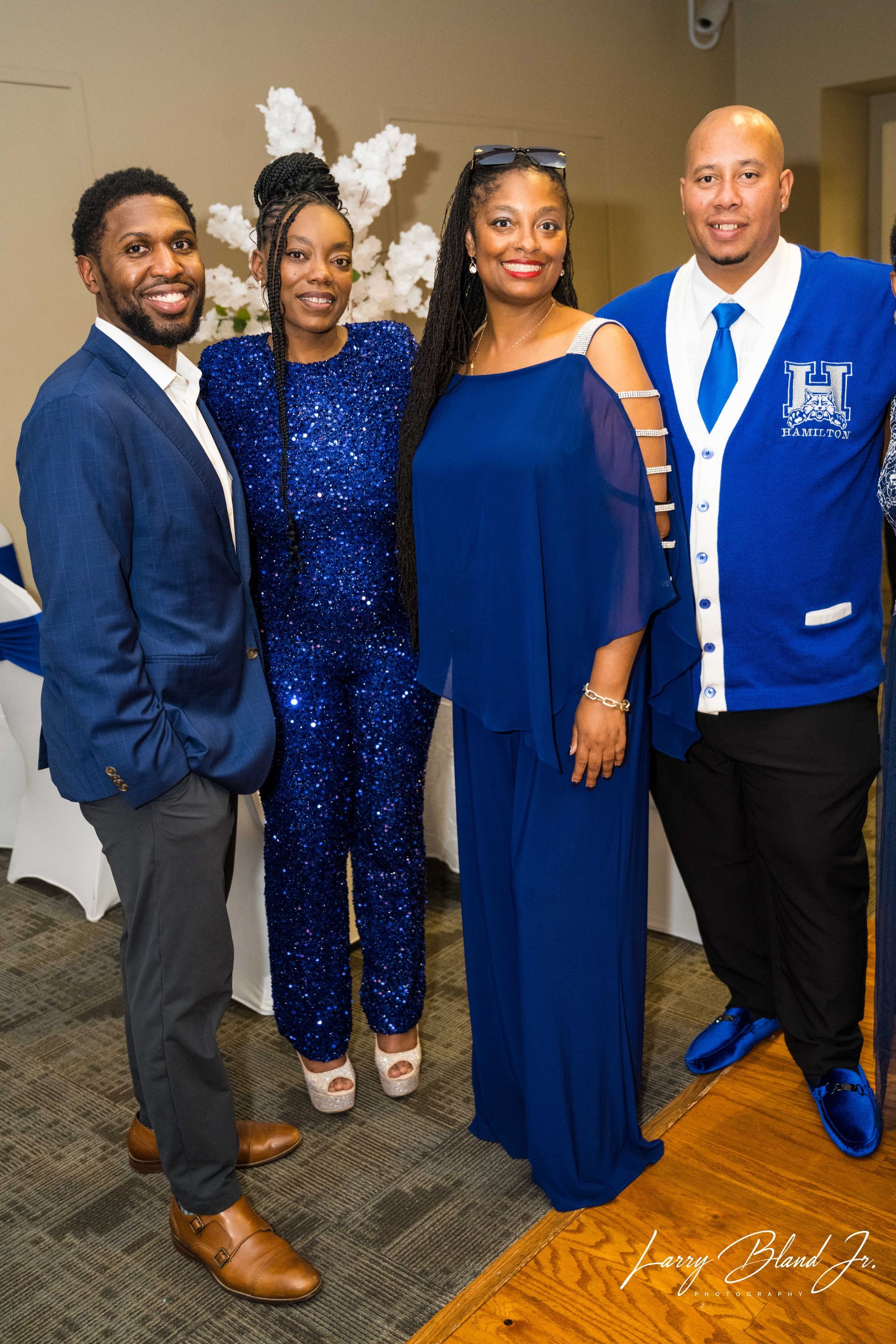 Four people in formal blue attire at an event, posing and smiling.