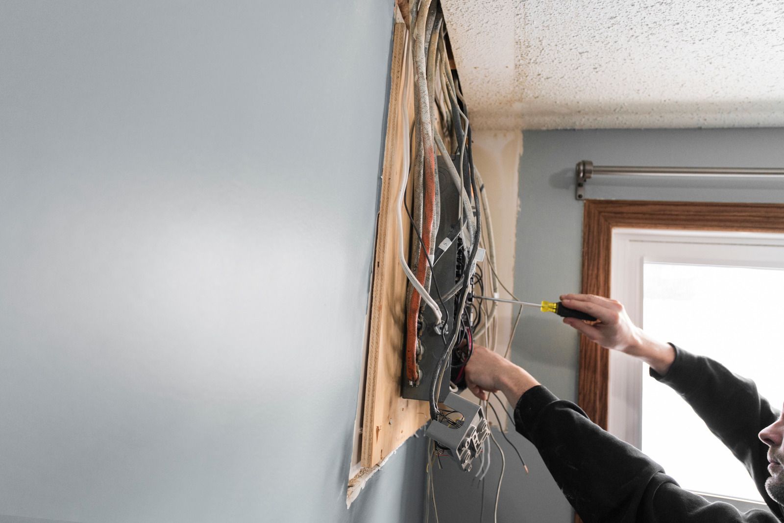 A man is working on a wall with a screwdriver.
