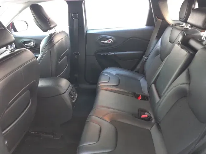 Rear interior of a black Jeep Cherokee, showing back seats with headrests and seatbelts.