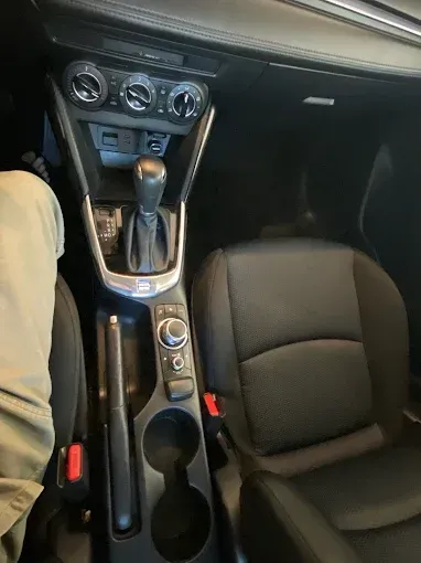 Interior view of a black car with a gear shift, seats, and controls visible.