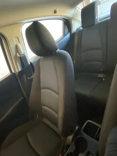 Interior of a car's backseat: gray and black seats, headrests, and a cup holder.