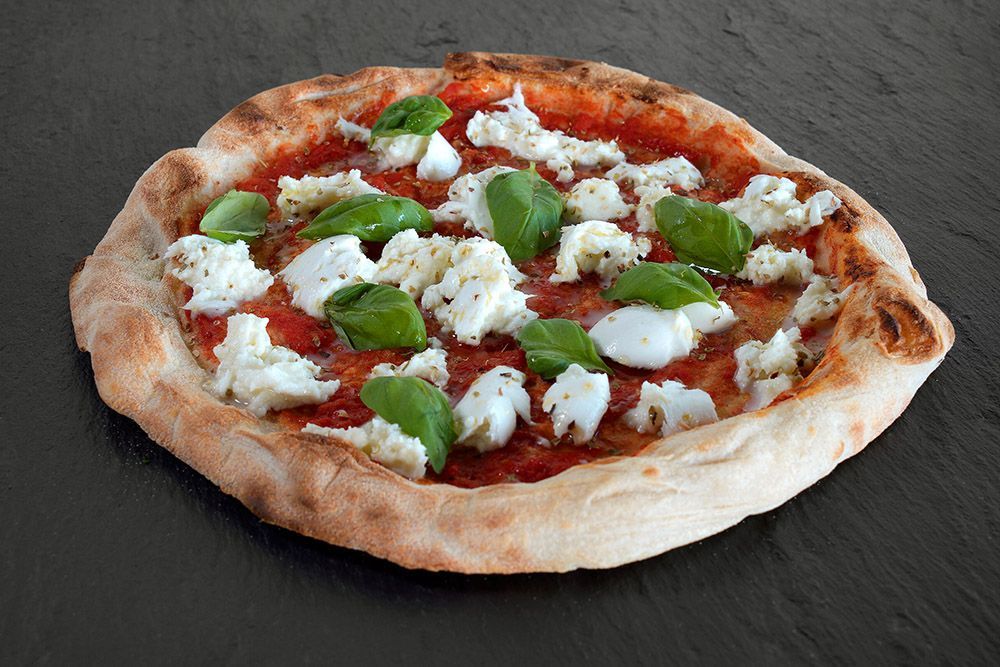 Pizza topped with green peppers and white cheese on a dark surface