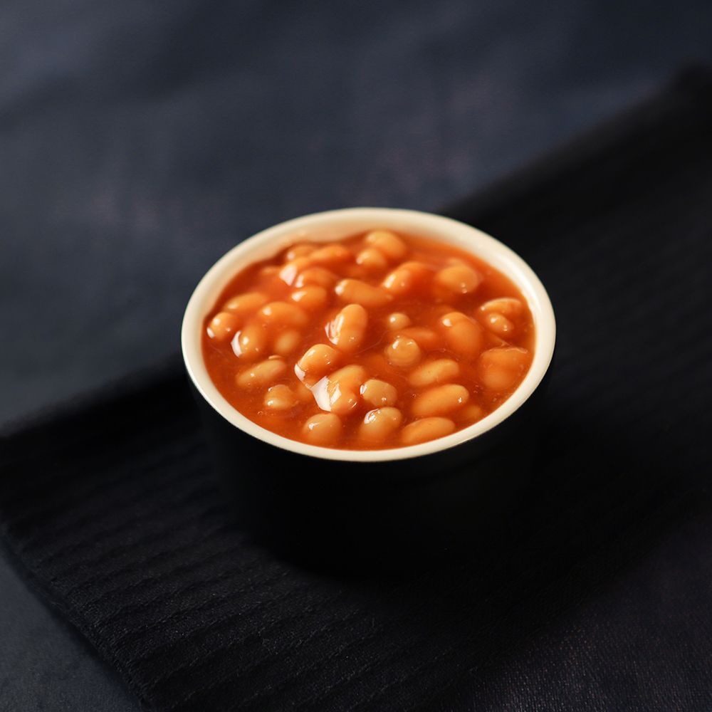 Small bowl of baked beans in tomato sauce on a dark cloth background