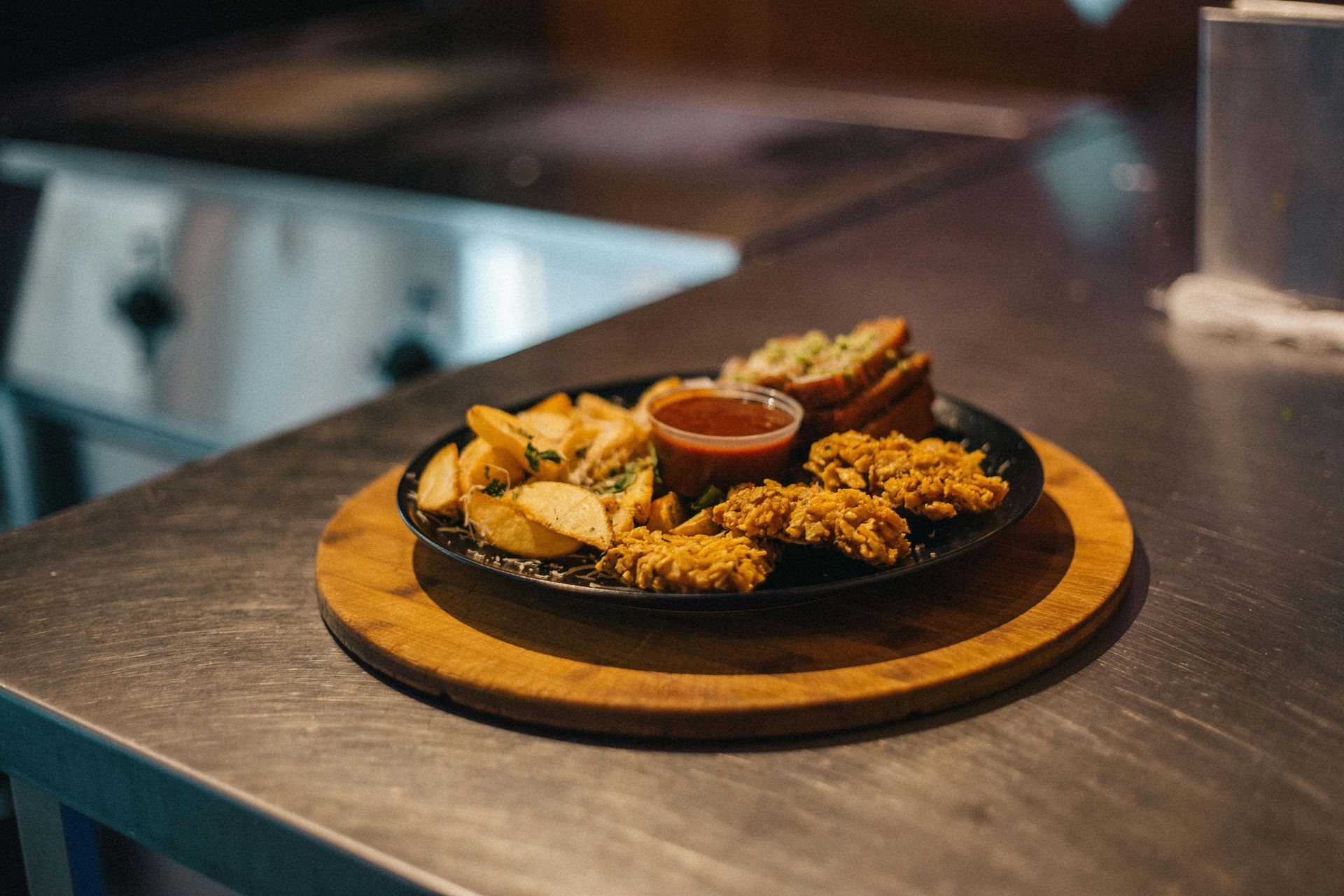 Plate of assorted fried appetizers with dipping sauce on a wooden board at a restaurant table