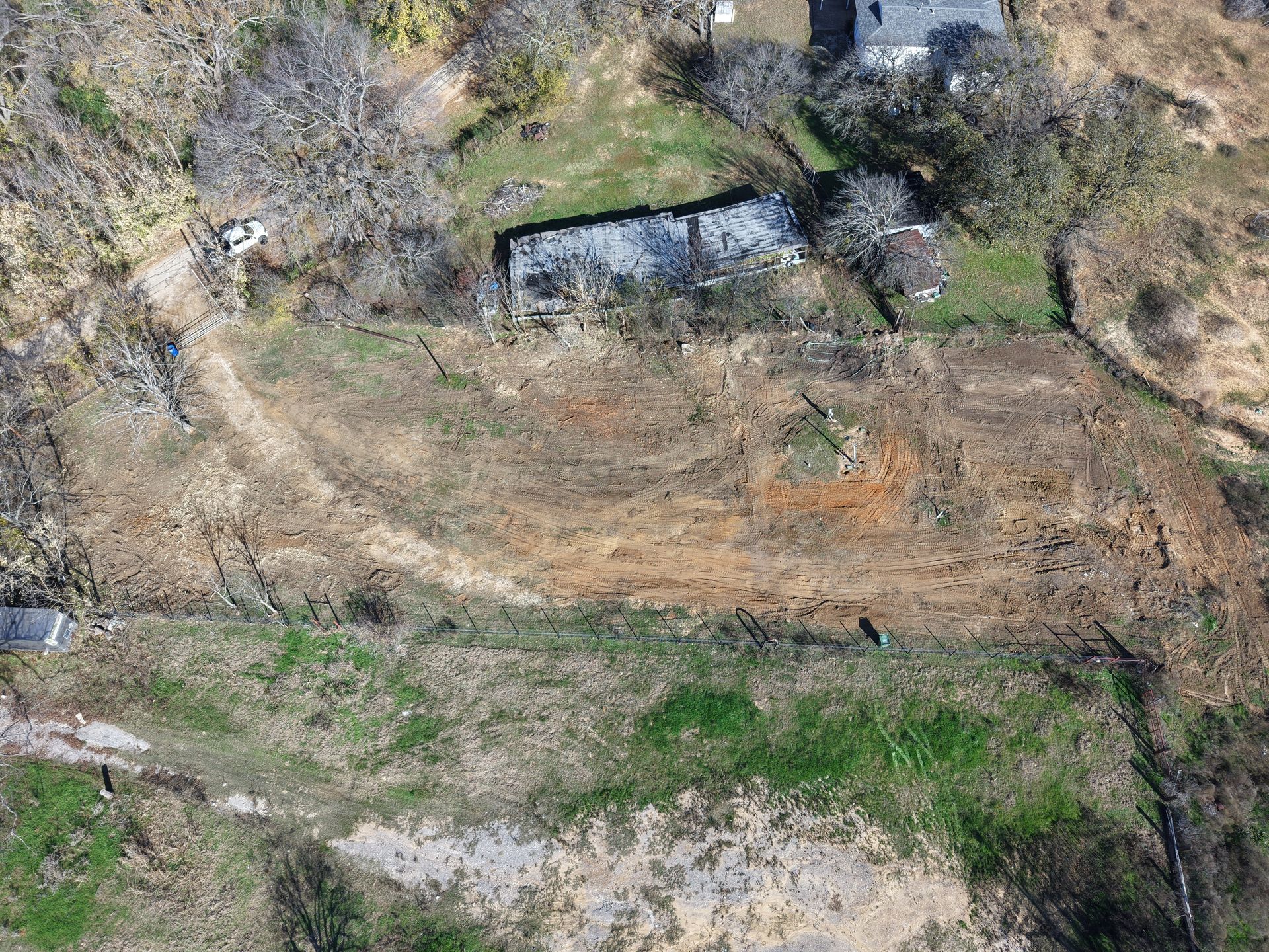 Rocky hillside with dry grass, scattered green patches, and a small stone wall across the center