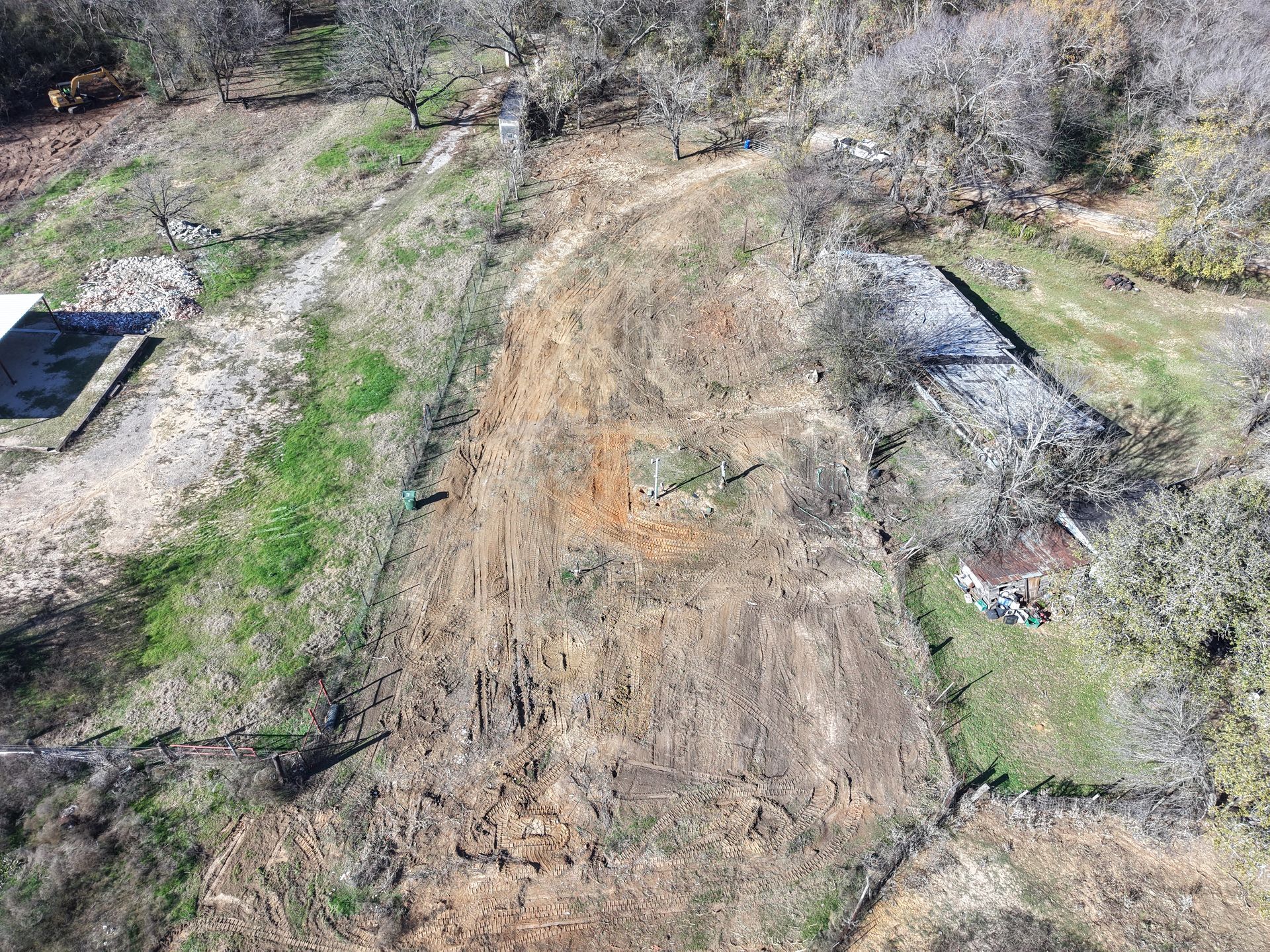 Damaged dirt hillside with a large landslide scar and sparse trees on both sides