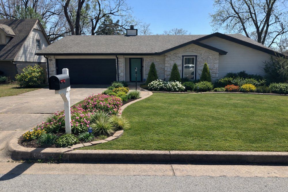 Single-story suburban house with a manicured lawn, flower bed, and driveway mailbox.