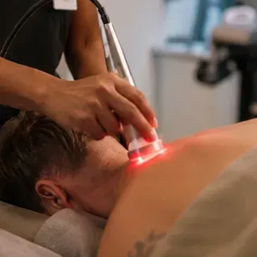 Person receives red light therapy on the neck from a handheld device in a spa setting