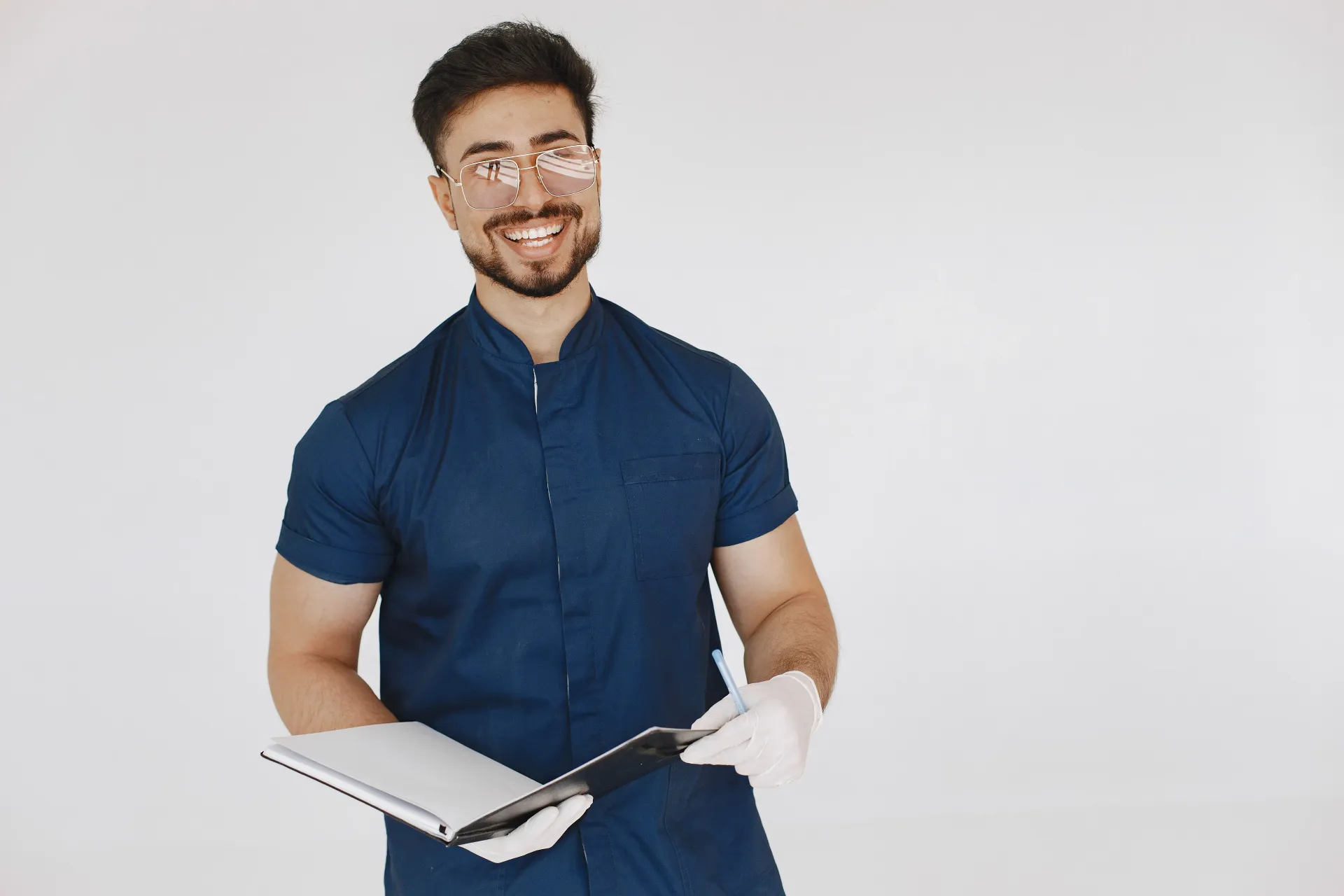 Smiling man in blue shirt holding an open notebook against a white background
