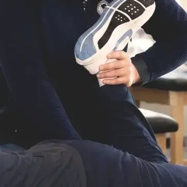 Person holding up a sneaker during what appears to be a shoe fitting or exam test.