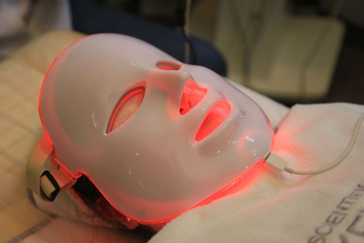 Person wearing a glowing white facial treatment mask with red light therapy