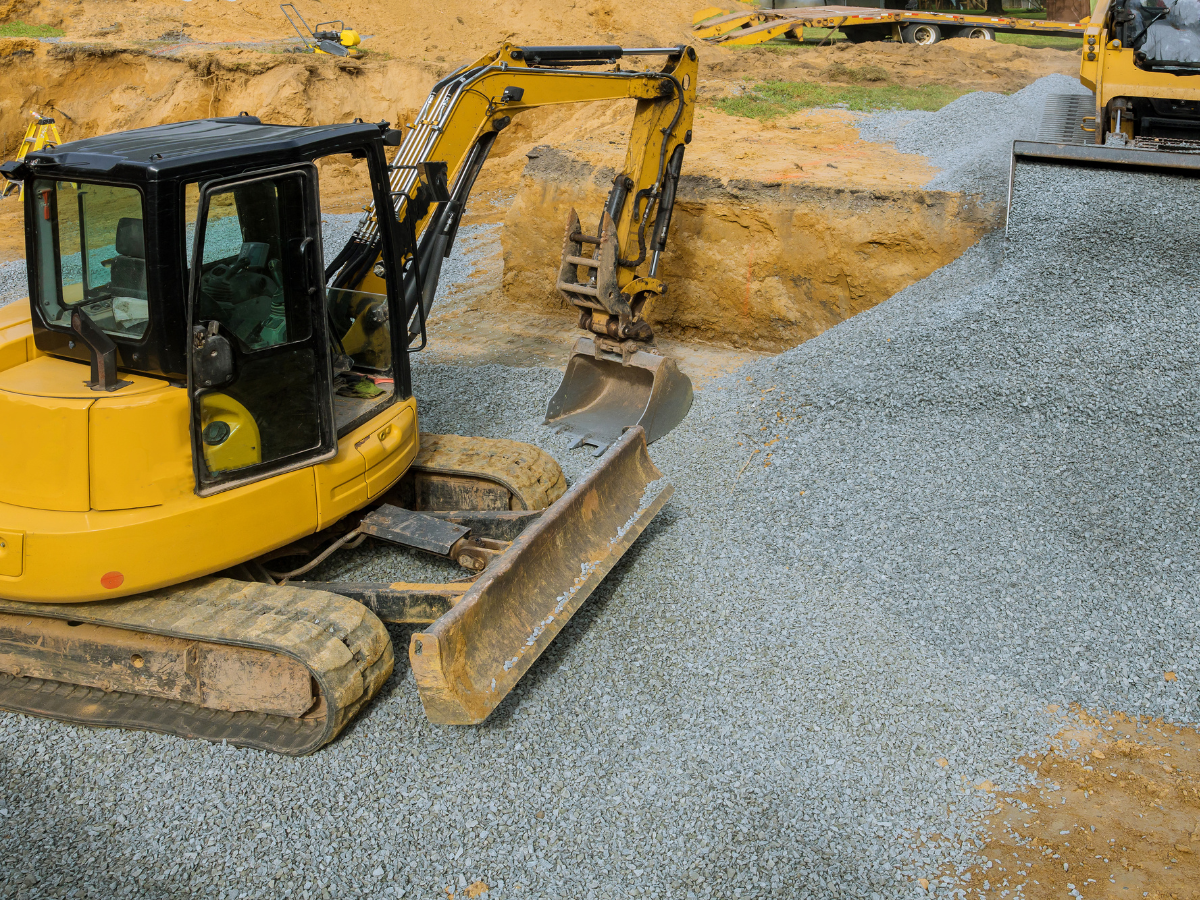 A yellow excavator is moving gravel on a construction site. A yellow excavator is moving gravel on a construction site.