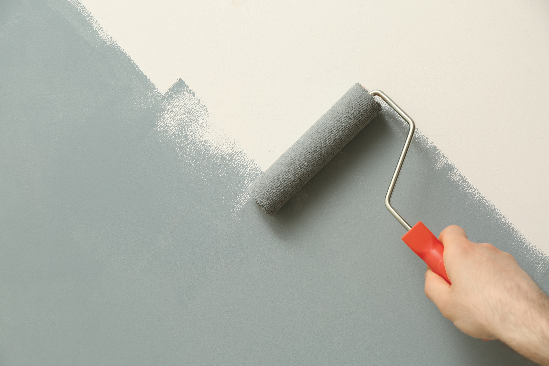A person is painting a wall with a paint roller.