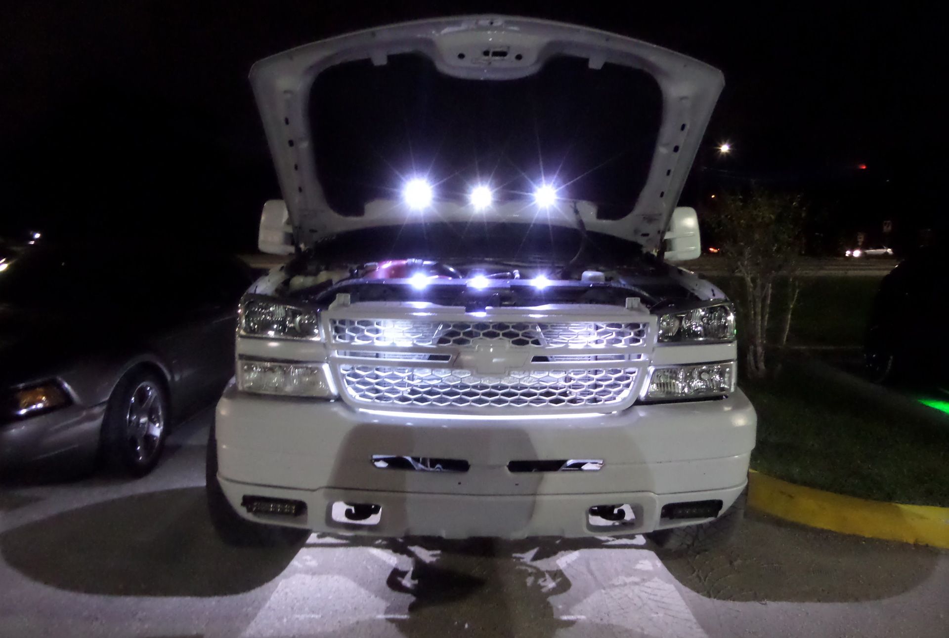 A white truck with the hood up and lights on