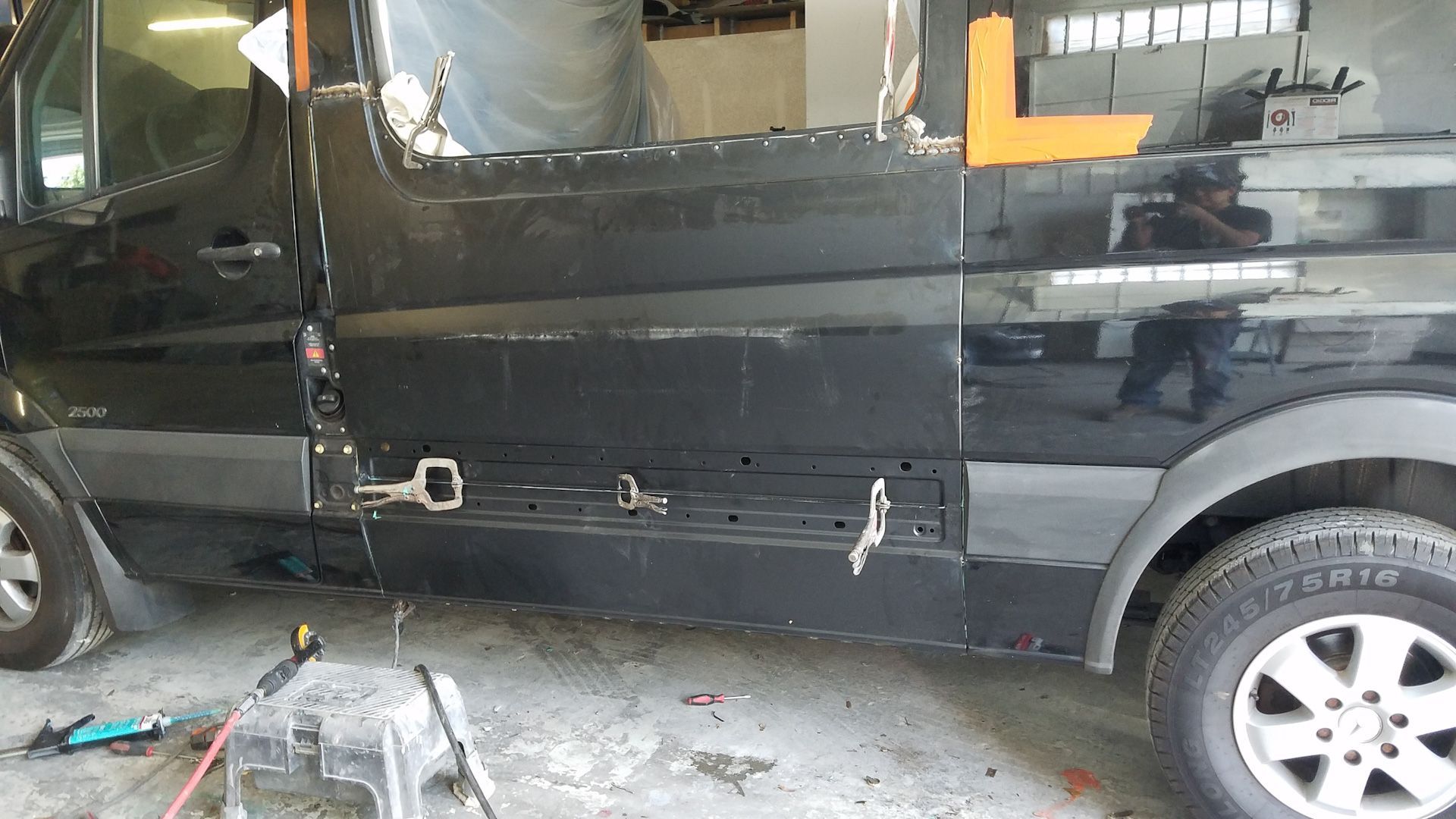 A black van is being repaired in a garage.