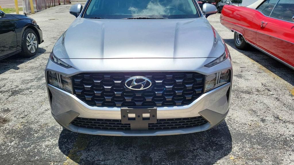 A silver hyundai santa fe is parked in a parking lot next to a red car.