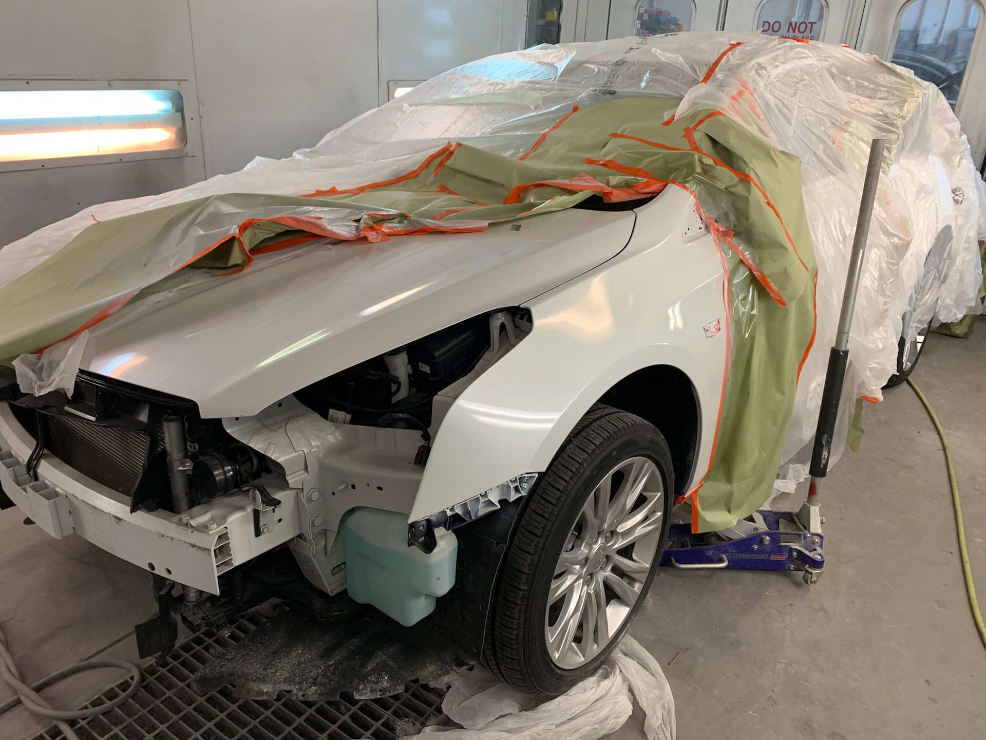 A white car is being painted in a garage.