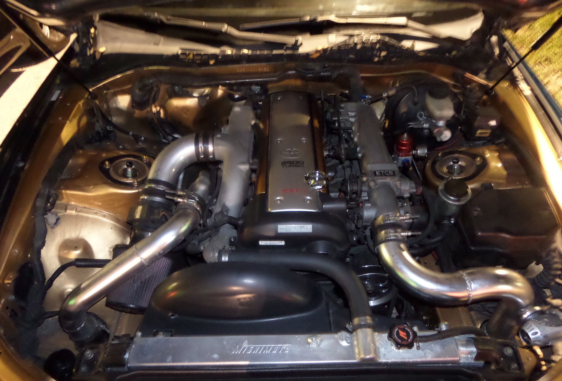 A close up of a car engine with the hood open