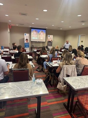 Conference room with people seated at tables watching a presentation on a screen
