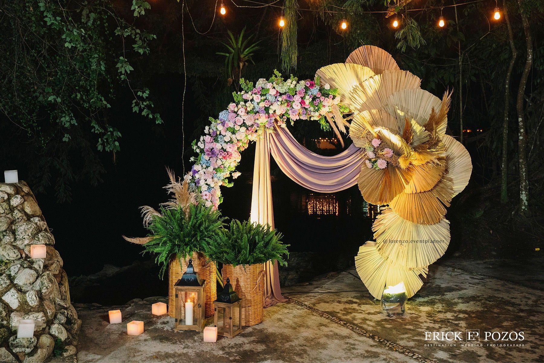 Un arco de boda decorado con flores y velas en el bosque.