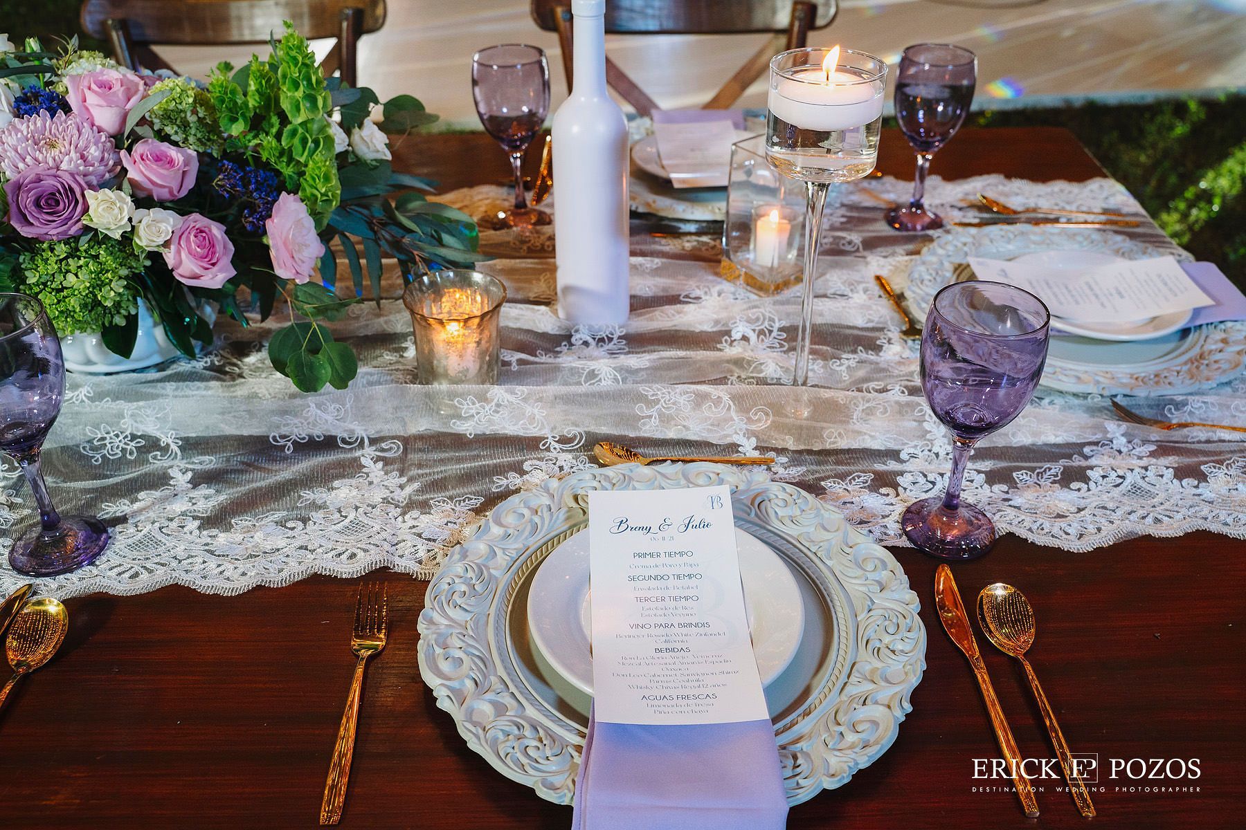 Una mesa con platos, vasos, velas y flores sobre ella.