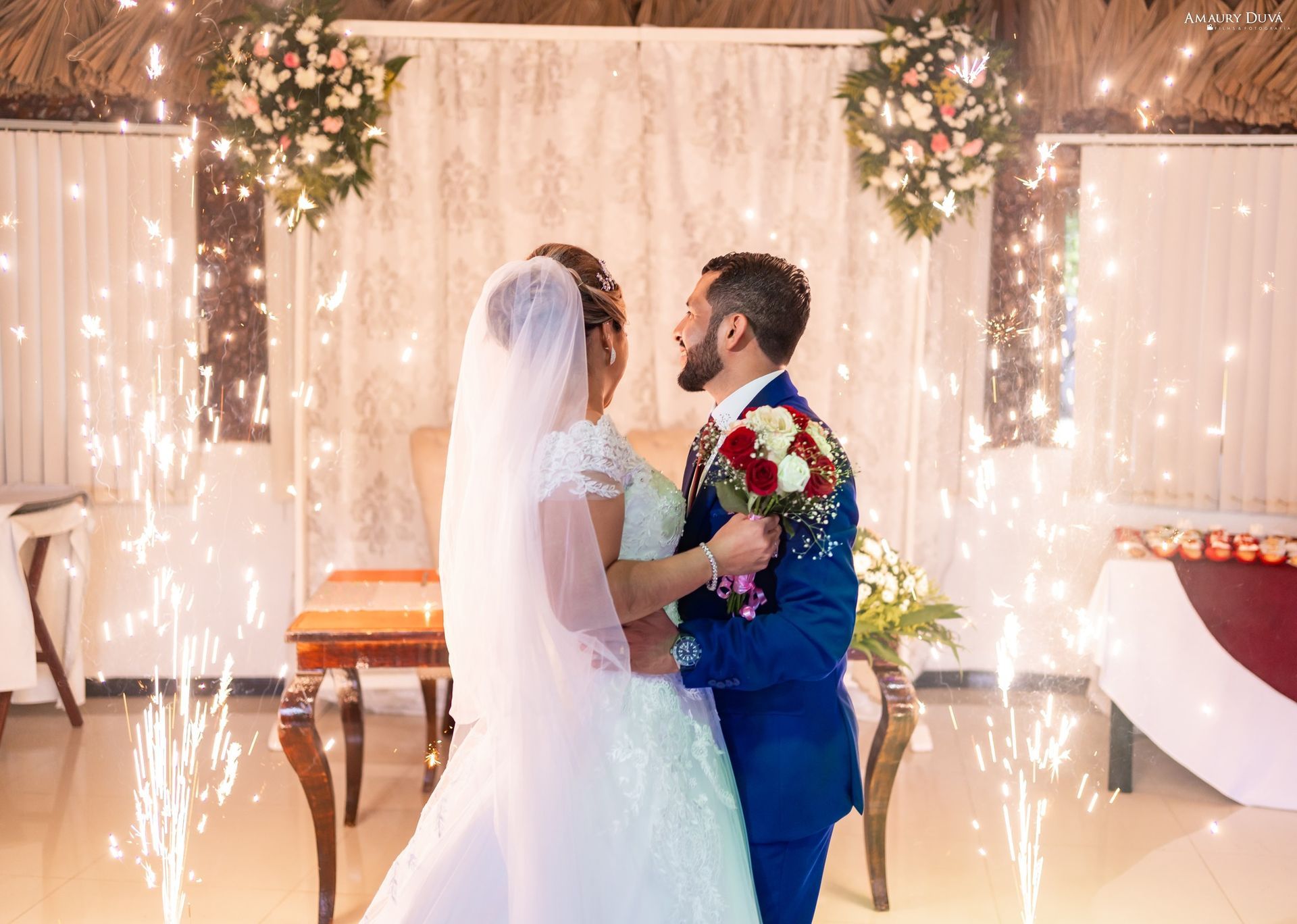 Una novia y un novio se besan frente a bengalas en su boda.